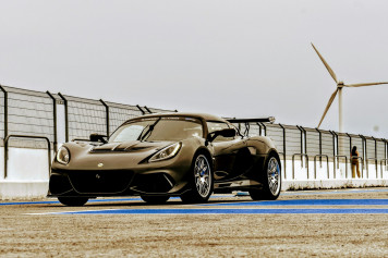 a brown sports car driving past a wind turbine