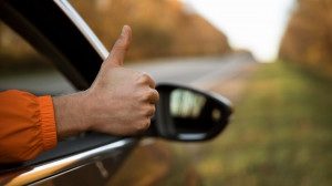man giving thumbs up out of his car while on a road trip